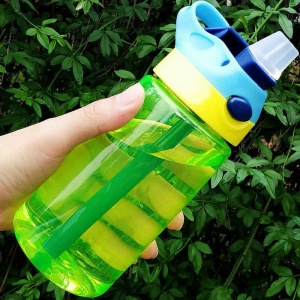 480 ml läckagefri flaska med lock och sugrör i grönt, gult och blått framför ett träd