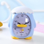 Fågelformad väckarklocka för barn på ett vitt bord och blå bakgrund