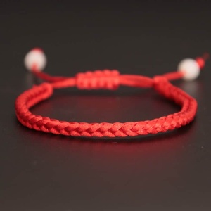 Armband i handvävt rött rep mot svart bakgrund