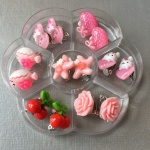 Set med 7 clipsörhängen för barn i rosa, i en transparent avdelare med vit bakgrund