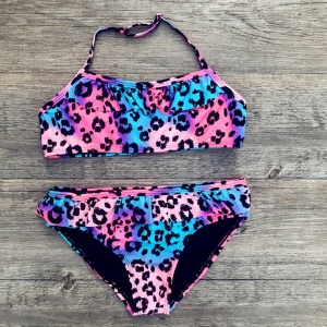 2-delad baddräkt med leopardmönster för flickor i rosa, lila och blått på grått trä