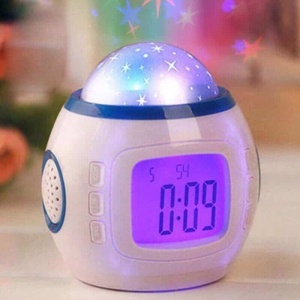 LED-väckarklocka med flerfärgat stjärnljus och digital front på ett träbord