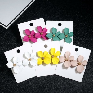 Blomformade örhängen för flickor i vitt, gult, rosa och grönt med etikett mot svart bakgrund