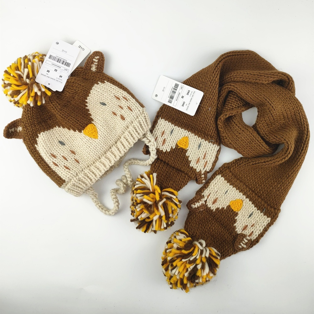 Brun och beige stickad barnmössa och halsduk med fågelmotiv mot vit bakgrund
