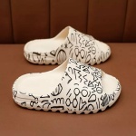 Bekväma sommarflip-flops för alla i vitt med svart em-mönster på en brun hylla