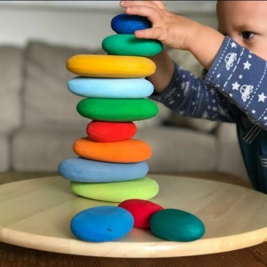 stapelbara leksaker av färgade stenar för barn på en träplatta