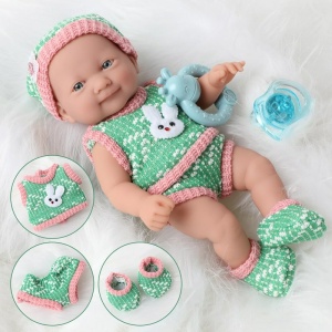 Mjuk docka för nyfödda med gröna och rosa kläder på en vit kappa