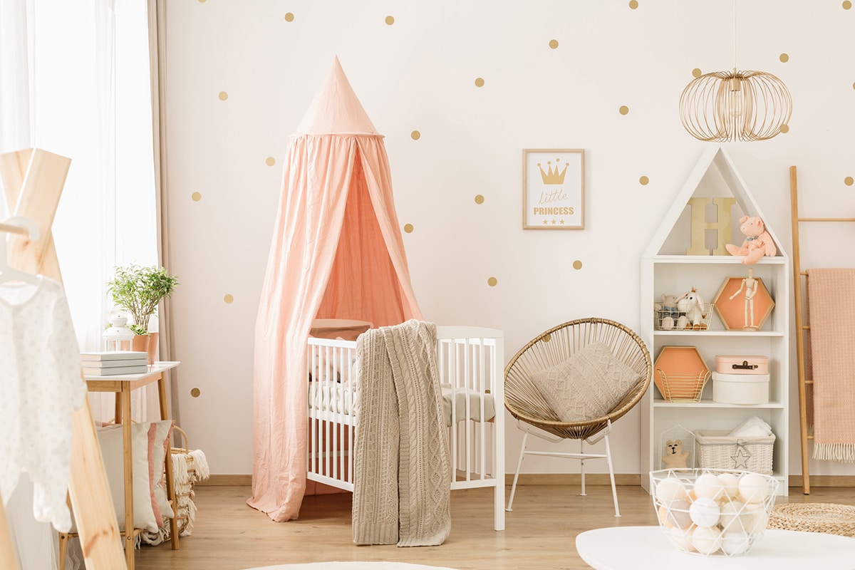 Ett städat sovrum för barn. Rosa toner, en barnsäng, förvaringsmöbler och dekorationer.