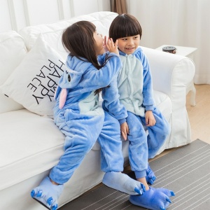 Varm tecknad pyjamas med blå sömmar för barn med 2 barn på en vit soffa