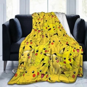 Pokémon-filt med Pikachu-motiv för barn på en svart soffa framför ett fönster