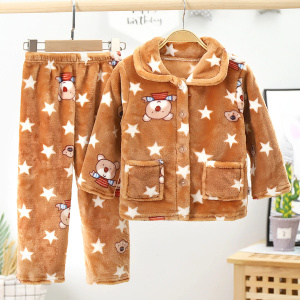 Pyjamas i fleece med stjärnor och ränder för barn i brunt och vitt med mönster i ett sovrum med en växt bakom