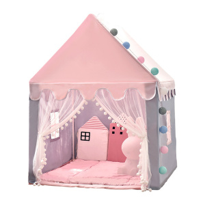 En barntepe i form av ett rosa litet hus, med öppen framsida och två gardiner som hänger ner längs sidorna. Det finns små fönster på sidorna. Inuti finns ett rosa vadderat golv och rosa kuddar.