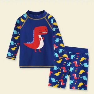en uppsättning badbyxor, shorts och en blå t-shirt för barn med ett dinosauriemotiv på en beige bakgrund