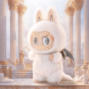 Vit Labubu-plysch med kaninöron, silverfärgade drakvingar och stora glänsande ögon, stående mot en ljus himmelsblå bakgrund.